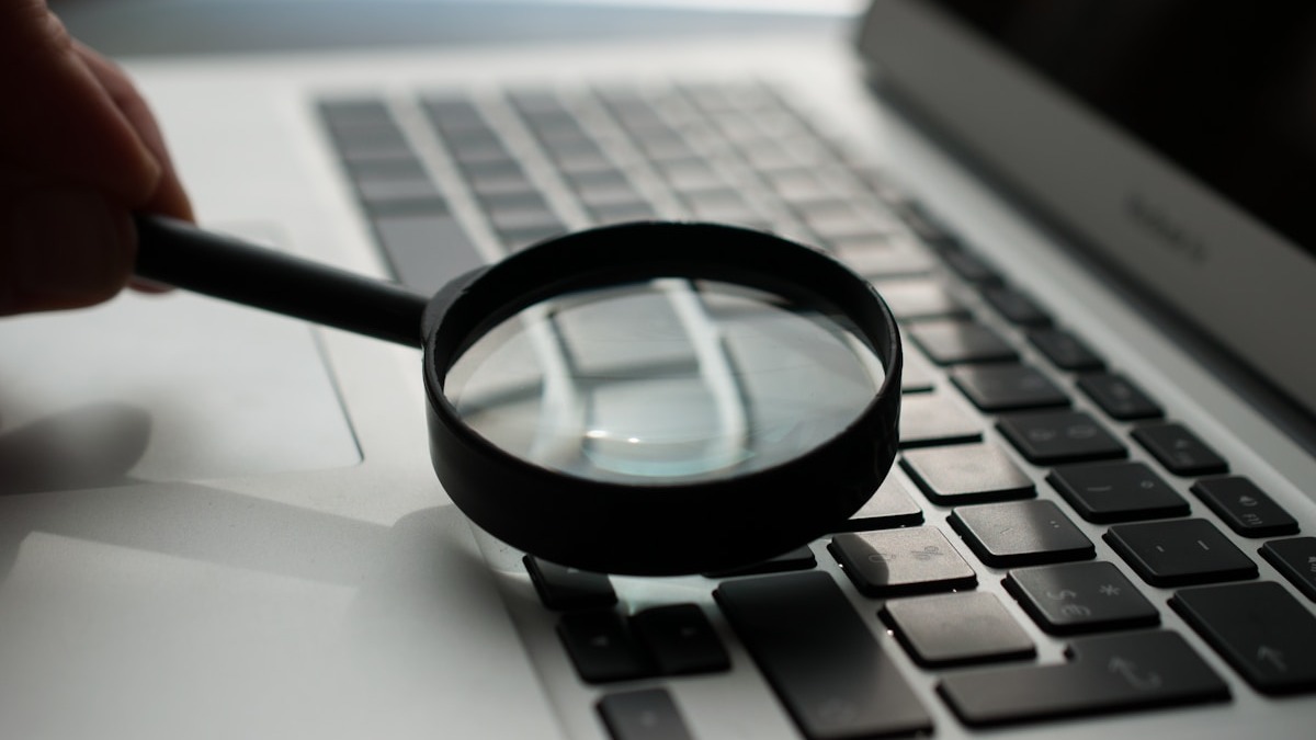 A magnifying glass over a laptop screen representing close scrutiny of agent behavior