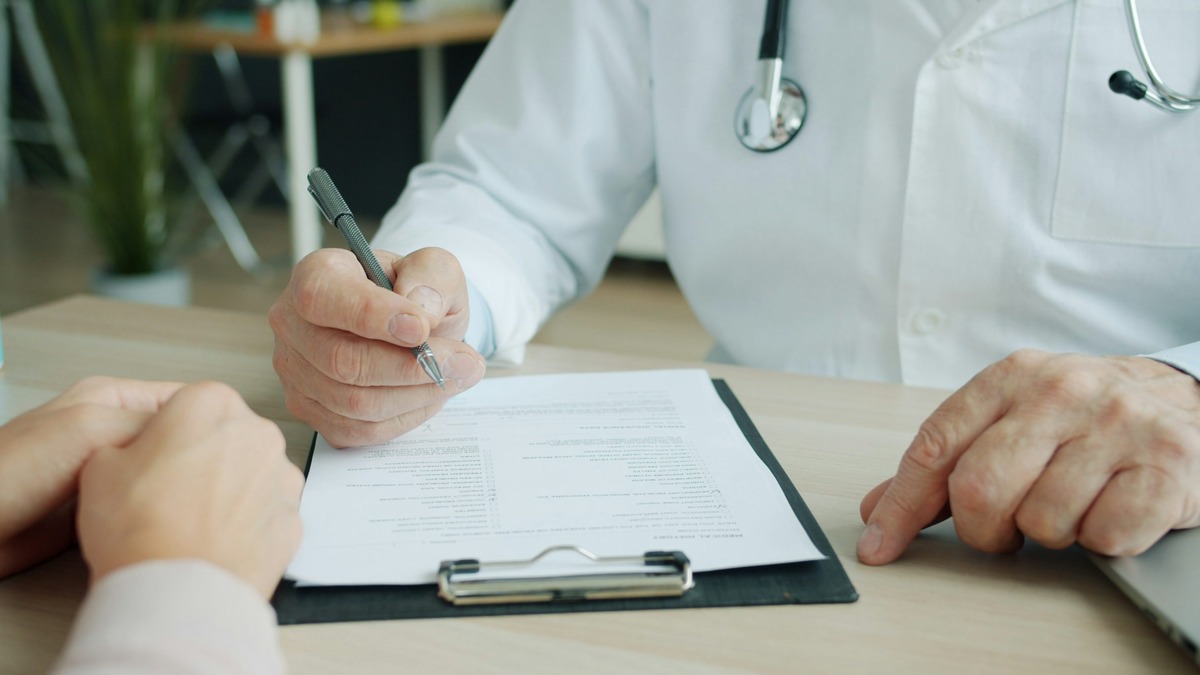A doctor reviewing a patient chart with a stethoscope visible