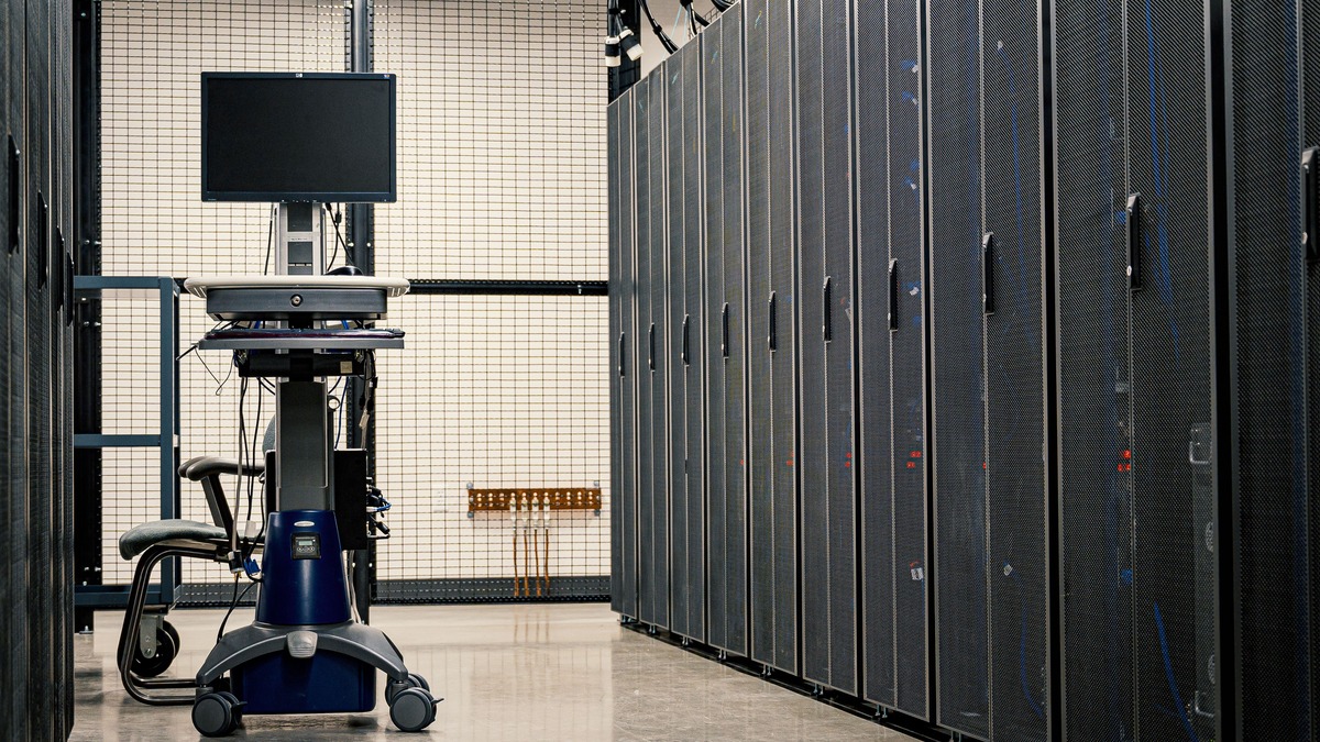 A data center aisle with server racks and a workstation on wheels