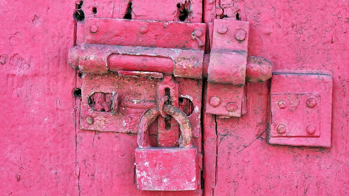A rusted padlock on a weathered door
