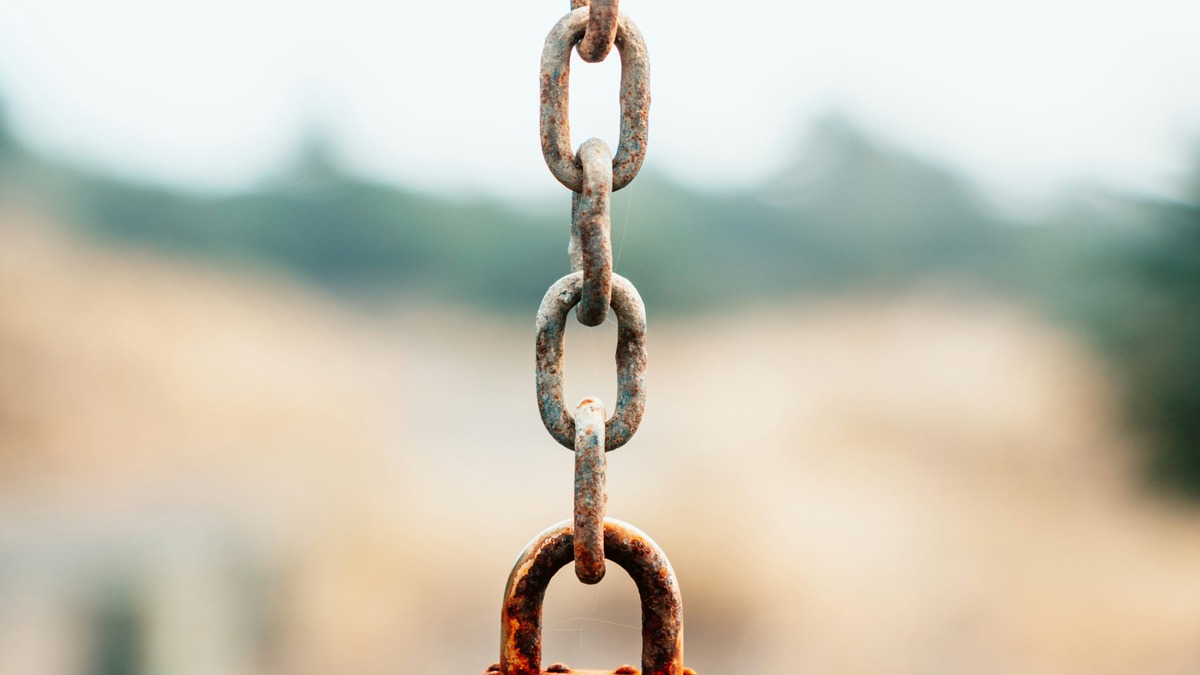 Rusted padlock hanging from a metal chain