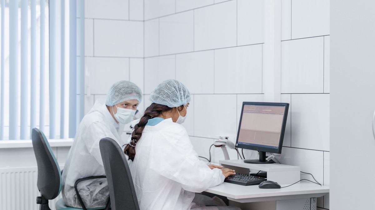 A researcher examining data on a laptop in a laboratory setting