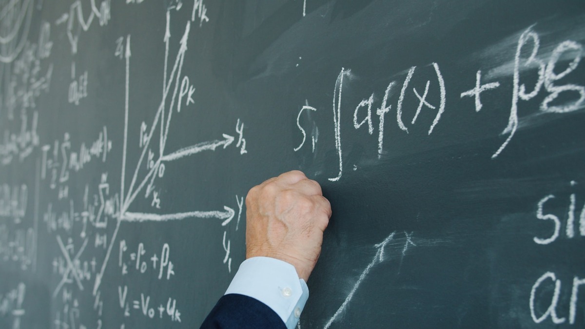 Hand writing mathematical formulas and diagrams in chalk on a blackboard