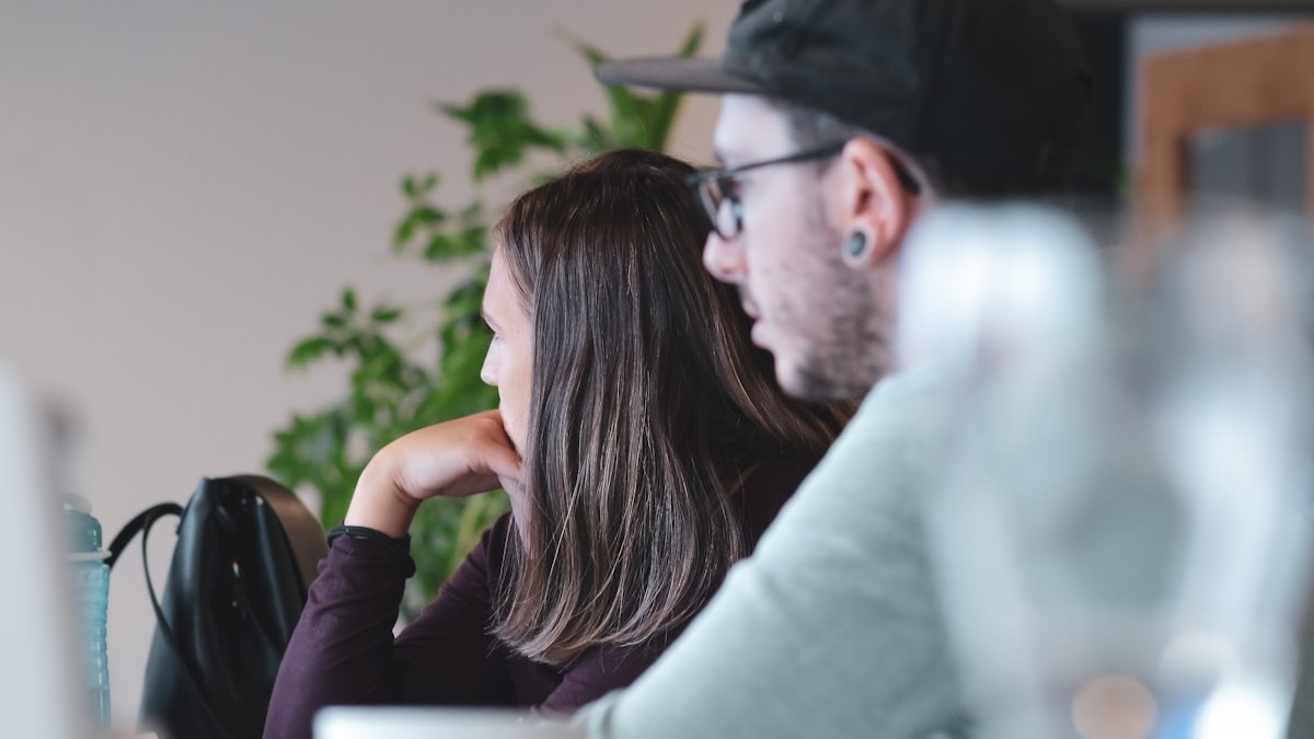 Two developers reviewing code together at a shared workstation in a bright office