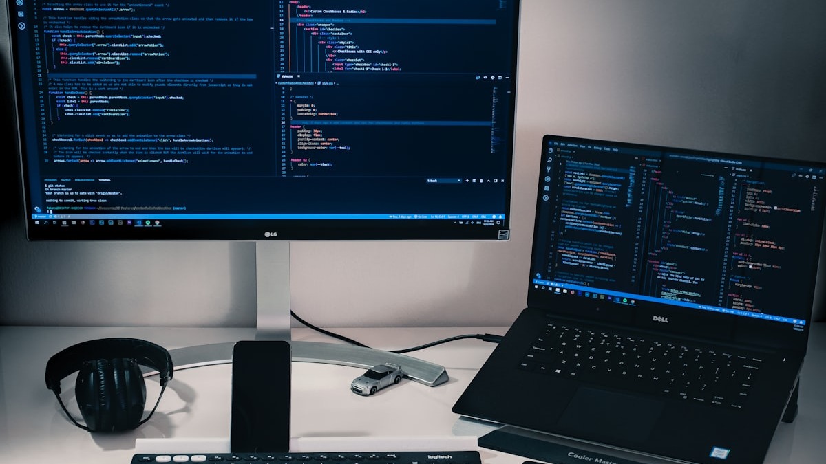 Developer workstation with dual monitors showing code in VS Code and terminal windows