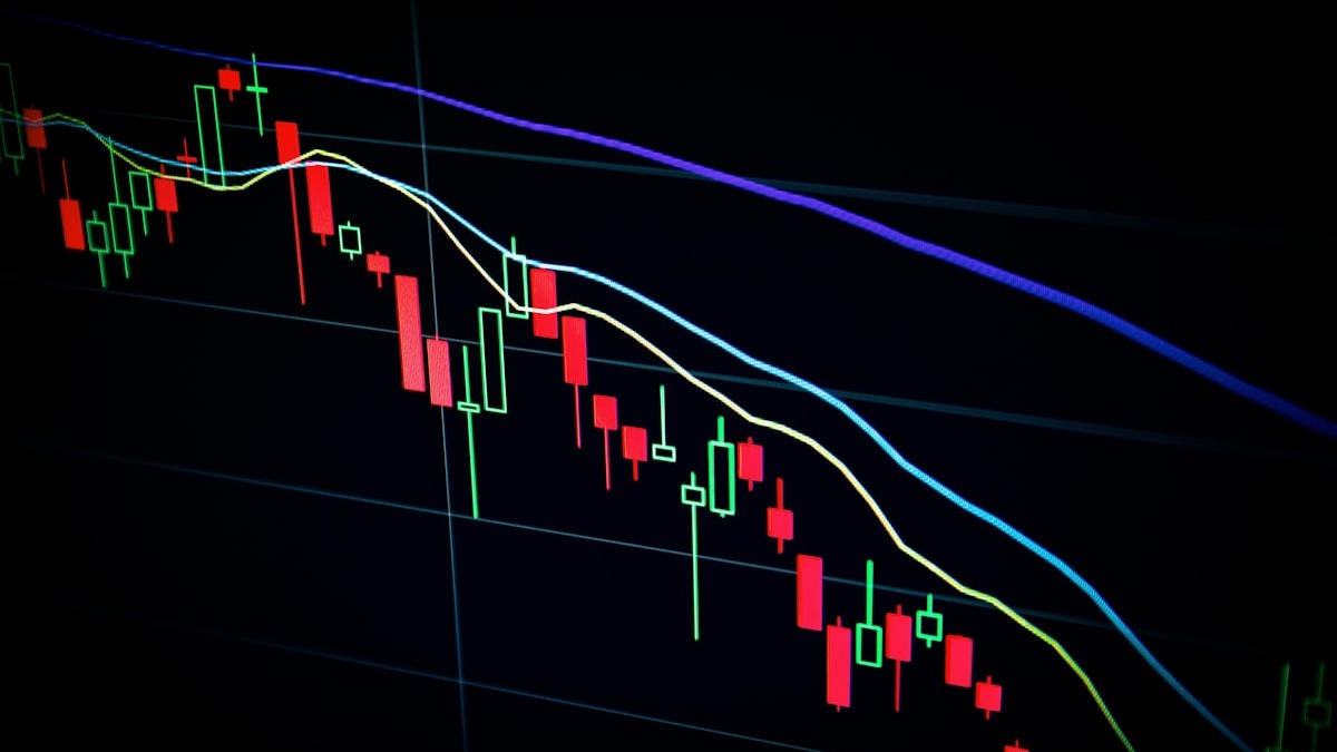 Stock market charts and trading data on multiple screens showing analytics dashboards