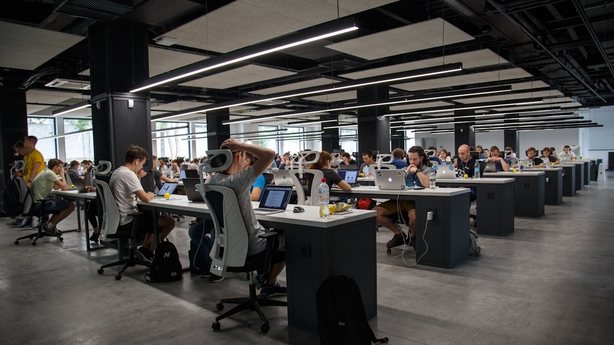 A sales team collaborating in a modern office with laptops and data dashboards visible on screens