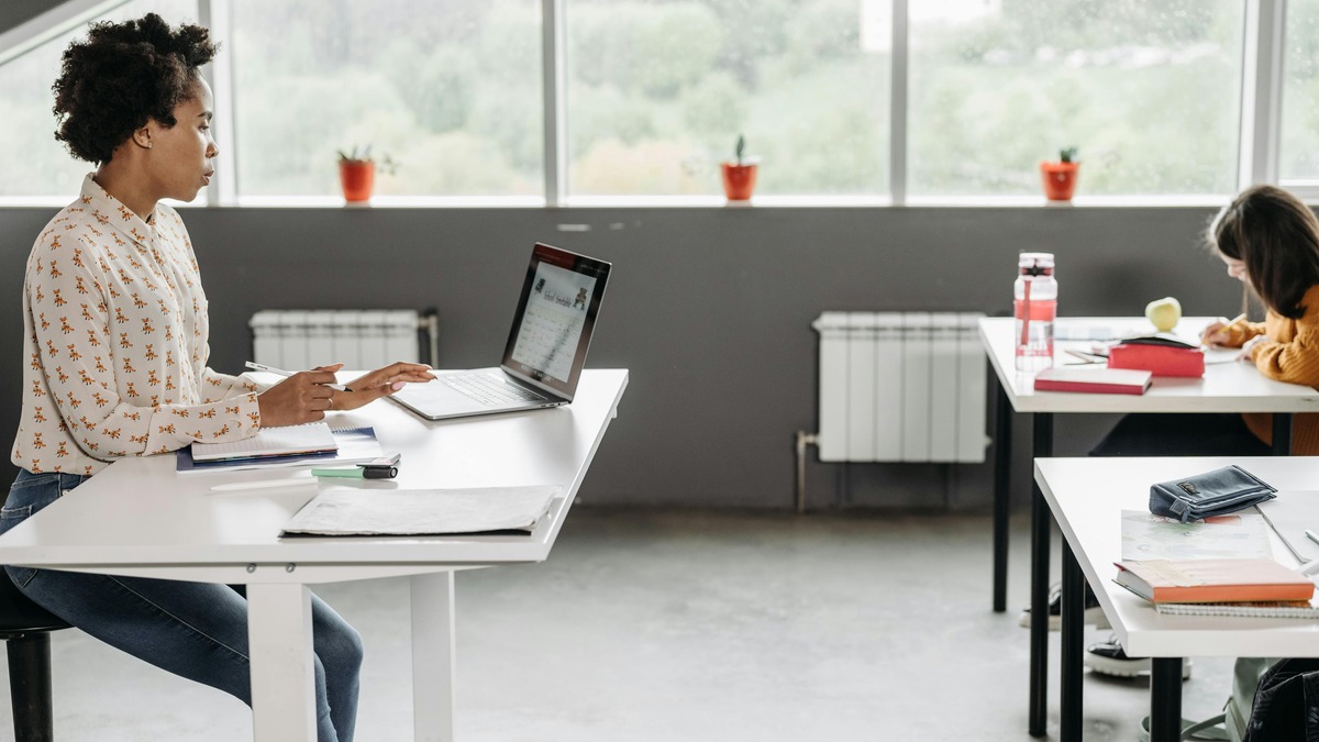 A teacher using a laptop in a modern classroom, using an AI planning tool