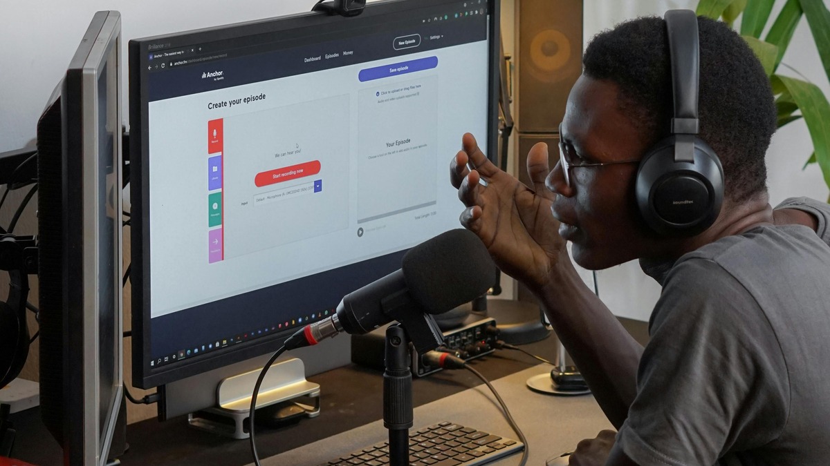 A man wearing headphones recording at a professional microphone setup