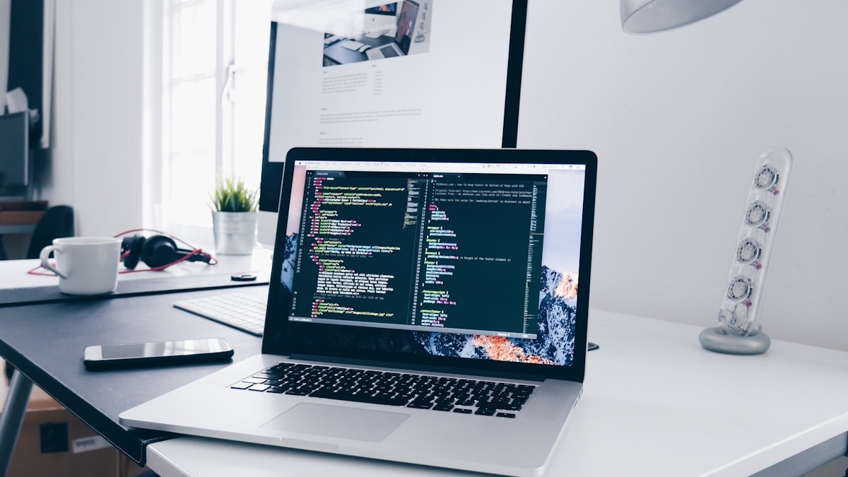 Person writing code on a laptop with multiple browser tabs visible, web development in progress