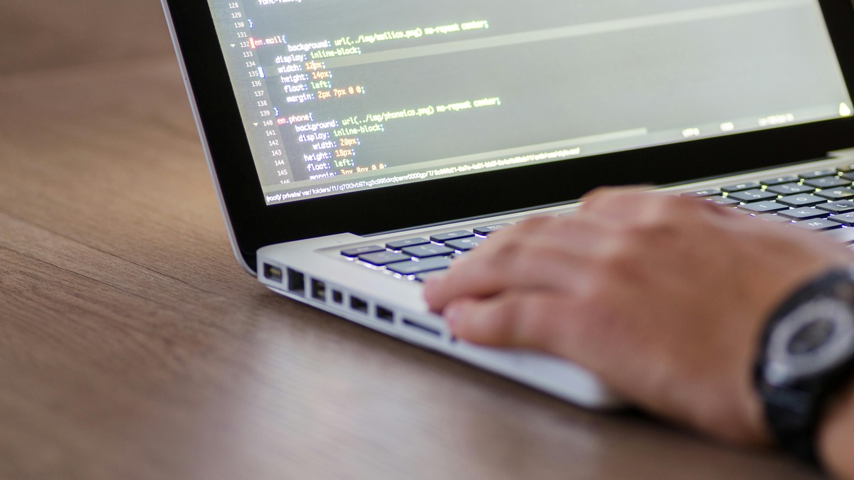 Developer working at a coding setup with multiple screens