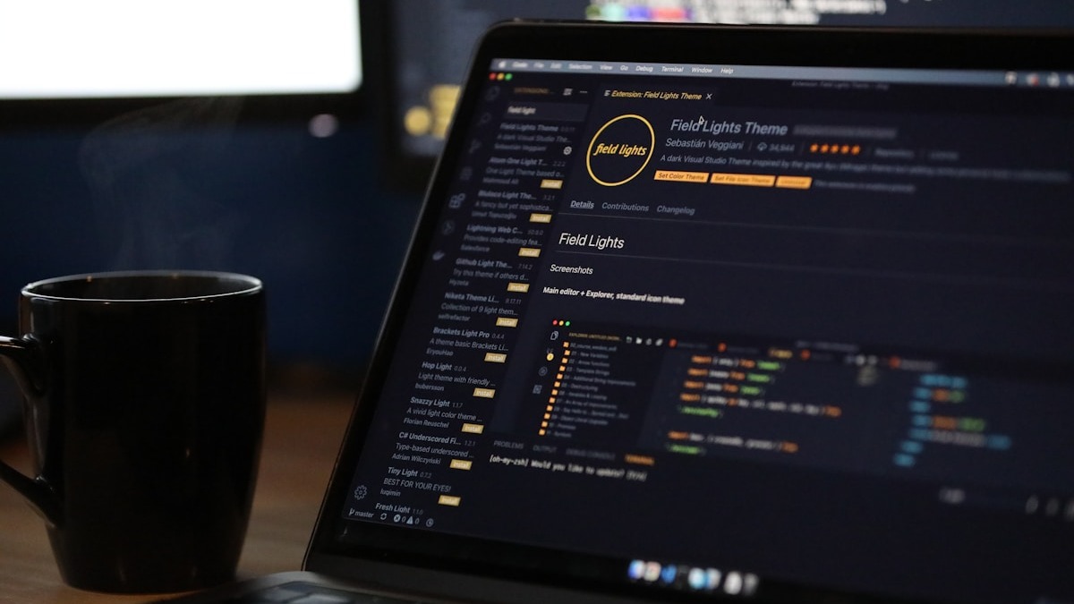 Two developers collaborating on code displayed across multiple monitors
